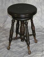 Front and side view of the dark brown adjustable piano stool showing circular seat and four turned legs with brass claw and ball feet.