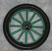 Green Ford Model T wheel with black Goodyear tire, showing some wear and wooden cracks