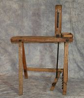 Side view of the wooden harness maker’s stitching horse showing angled legs, clamp vertical arm and metal connecting rod.