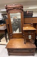 Photo of dresser with large framed mirror, three drawers with metal handles, carved wood top detail, showing surface wear and loose leg on one drawer