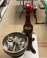 Full view of red cream separator with separate metal bowl containing 32 parts.