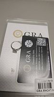 Moissanite ring placed on a GRA certification card and paperwork showing certification details.
