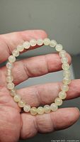 Natural white jade 6mm bead bracelet held in hand showing size and bead detail.