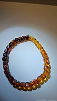 Bracelet laid flat showing gradient color transition from dark to light amber beads.