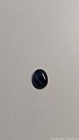 Photo of 1.72ct oval blue star sapphire cabochon showing natural dark blue color and smooth surface.