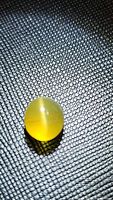Photo of natural catseye Apatite oval cabochon gemstone showing catseye effect on textured black background.