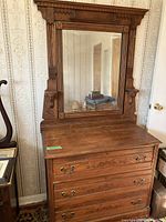 Front view of entire antique dresser with attached mirror showing wood finish, drawer handles and detailed mirror frame