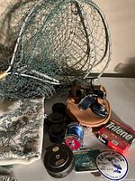 Full view of the lot showing three fishing nets, a folded blanket, multiple fishing reels including the Intrepid Rimfly reel, and fishing line spools