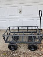 Full view of Yardworks garden cart showing metal mesh base and sides, four large knobby black tires, and handlebar.