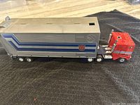 Side view of red cab and silver trailer on black surface