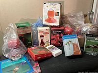 Group photo showing multiple hummingbird feeders, butterfly feeder box, and hummingbird book arranged on table