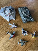 Overview of all seven military-themed toy items: army tank, fighter craft, and five miniature planes.
