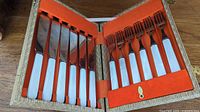 Full set of 6 butter knives and 6 salad forks with mother of pearl handles arranged in original orange lined box.