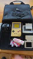 Photo of the yellow Nintendo GameBoy console, cables, and accessories all placed in a black carrying case.