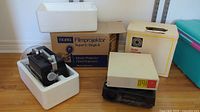 Noris Super 8 and Single 8 Film Projector in original styrofoam packaging next to Kodak Carousel slide projector in original boxes.