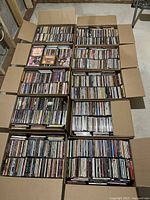 Overview of eight open cardboard boxes filled with CDs