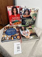 Four cookbooks displayed on a flat surface showing front covers: Nigella Lawson Christmas, Barefoot in Paris by Ina Garten, Baklava to Tarte Tatin by Bernard Laurance, and Nigella Lawson Feast.