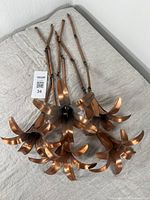 Five vintage copper flower-shaped pendant fixtures laid on a light surface, showing linked chain measurements and petal design detail.