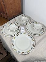 Set of 4 large vintage Duraline hotelware plates with retro leaf motif, each 9.25 inches in diameter on a cloth surface next to wooden furniture.