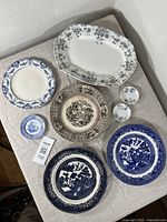 Full view of set on beige cloth, showing platter, plates, and butter pats together for scale and condition