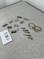 Photo of vintage cufflinks, tie bars and two wristwatches arranged on fabric, showing the variety of items and styles including silver and gold tones.