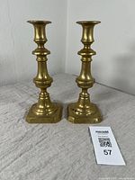 Pair of brass candlesticks standing upright showing design and size relative to the table surface.
