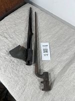 Photo showing the full bayonet and original leather sheath laid on a light cloth surface.