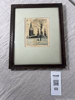 Framed aquatint print showing winter scene of Royal Archives building with snow, leafless trees, and monument statue. Dark wood frame with matting.