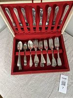 Full view of the open box displaying the assorted antique silver plate utensils held in velvet slots, showing knives, forks, and spoons.