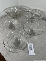 Five clear glass mixing bowls arranged, showing different sizes and ribbed patterns.