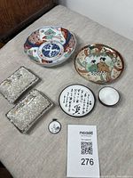 Overview of the 7-piece lot showing all items on a cloth surface including bowls, plates, dishes, cup, and pendant