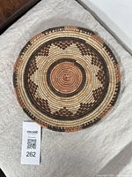 Top view of vintage coil woven flat plate basket with visible geometric zigzag pattern in natural earthy tones.