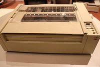 Front and side view of vintage Apple dot matrix printer A9M0303 showing beige casing and control buttons.