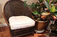 Front view of vintage bamboo wicker chair with cream cushion, showing woven backrest and cushion detail.