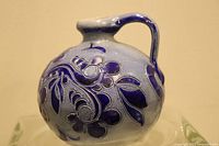 Photo showing front side of vintage cobalt blue glazed stoneware jug with detailed floral design and handle