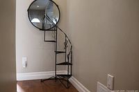 Full view of the stand placed in a corner against two walls with a round mirror above, showing overall shape and structure.