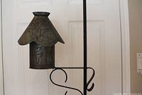 Close-up photo of galvanized metal light vessel with roof and hooks on stand