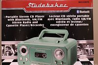 Close-up photo of the Studebaker stereo box highlighting Bluetooth, CD player, AM/FM radio and cassette player/recorder features in vintage green color.