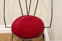 Close-up of round velvet cushion attached to twisted metal frame