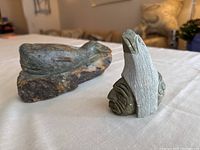 Photo showing both stone carvings on a white cloth background, highlighting the contrast between the textured surfaces and colors.
