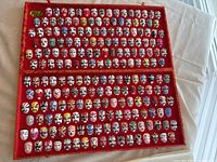 Full view of two-tier red fabric box containing 208 miniature painted masks representing facial makeup of Beijing Opera characters.