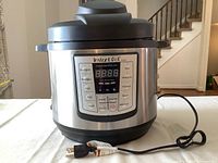 Front view of Instant Pot showing the digital control panel with cooking options buttons and power cord.