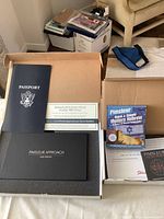 Photo showing Pimsleur Hebrew learning materials including a navy blue passport booklet, reading booklet, gold edition box, and workbook.