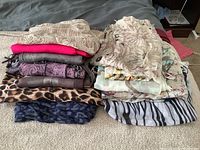 Overview of all 12 scarves laid out in two stacks showing different colors and patterns including animal prints and florals