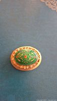 Front view of brooch showing green enamel center and gold decorative border