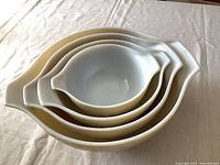 Top down view of all four nesting Pyrex bowls stacked inside each other on a beige cloth.