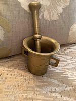 Mortar and pestle shown assembled with pestle upright inside the mortar, highlighting its solid brass composition and engraved pattern.