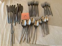 Photo showing an assortment of over 45 vintage Dansk cutlery pieces including knives, forks, and spoons in stainless steel.