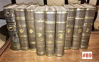 Front spine view of the 9 volumes showing aged brown leather binding with gold decoration, including 8 respined volumes and one original black spine.