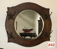 Full front view of the antique oak hall mirror showing round beveled mirror, dark oak frame, and four sets of decorative triple hooks.